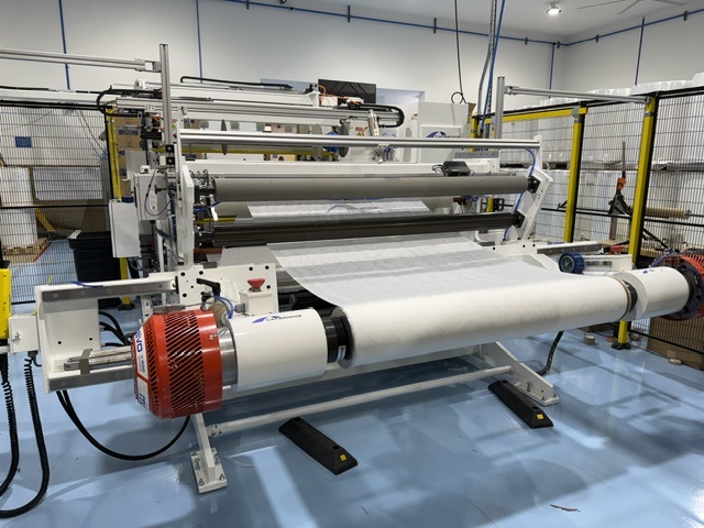 Shaftless floor pickup unwind stand at Pepin Manufacturing with a parent roll loaded and web feeding toward the slitter rewinder